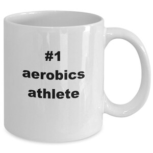 May include: White ceramic coffee mug with black text that reads "#1 aerobics athlete".