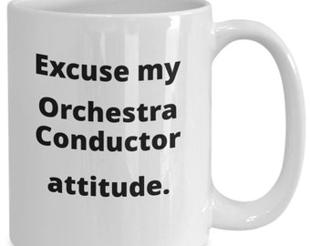 Op de afbeelding: Een witte keramische koffiemok met zwarte tekst die "Excuse my Orchestra Conductor attitude." luidt.