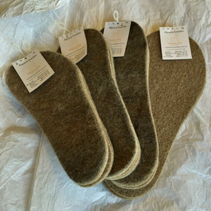 May include: A stack of brown alpaca insoles with a white label that reads "Alpaca Insoles" and lists sizes for women and men. The label also includes the text "Tibetan Tribe" and "Made in Peru".