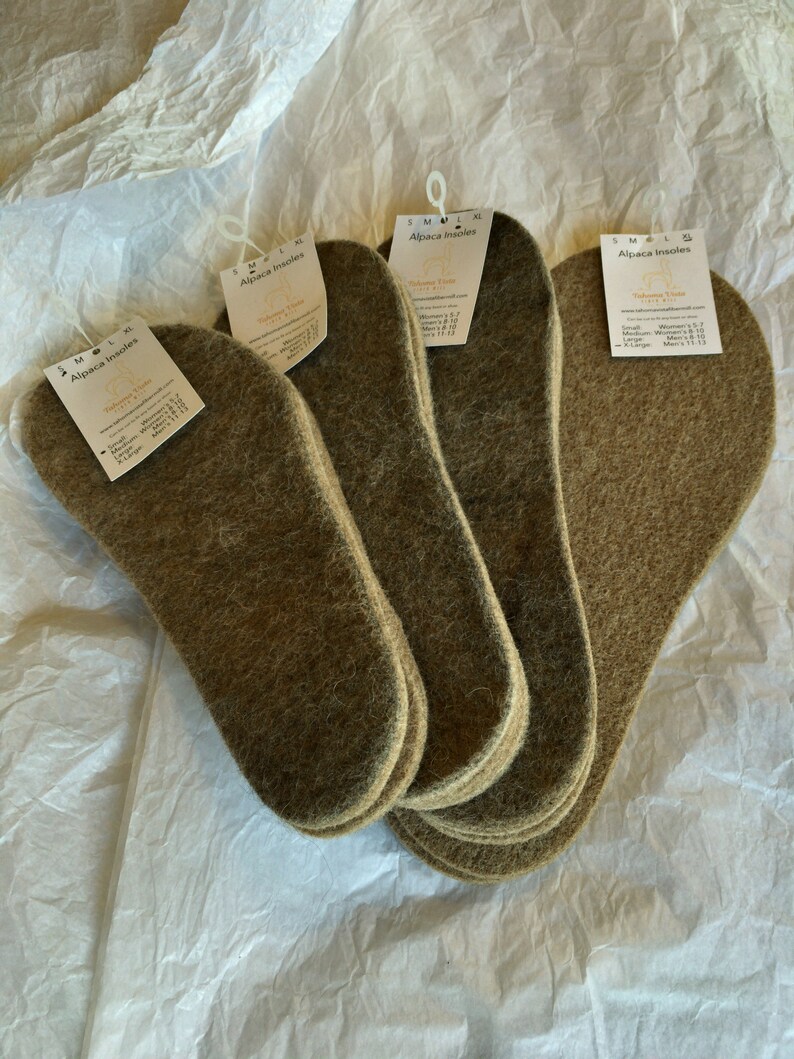 May include: A stack of brown alpaca insoles with a white label that reads "Alpaca Insoles" and lists sizes for women and men. The label also includes the text "Tibetan Tribe" and "Made in Peru".