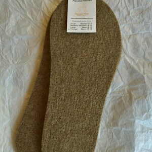 May include: Two brown alpaca insoles, made from natural fibers. The insoles are designed to be cut to fit different shoe sizes. The label reads "Alpaca Insoles" and includes sizing information for women's and men's shoes.