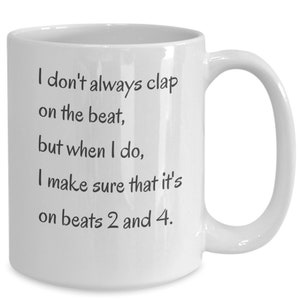 May include: White ceramic coffee mug with black text that reads: "I don't always clap on the beat, but when I do, I make sure that it's on beats 2 and 4."
