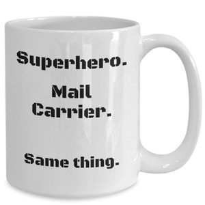 May include: White ceramic mug with black text that reads "Superhero. Mail Carrier. Same thing."