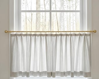 May include: A window with a white frame and a view of a forest. The window is adorned with a striped curtain in white and gray, hanging from a gold-colored rod. The curtain is made of vertical stripes.