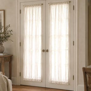 May include: Two off-white, semi-sheer door curtains made of a lightweight fabric. Each curtain is gathered on a thin, horizontal rod at the top and bottom, covering the glass panels of a set of double doors with a soft, filtered light effect.