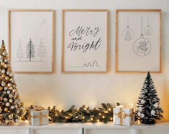 May include: Three framed art prints with Christmas themes. The prints feature line drawings of Christmas trees, ornaments, and the phrase "Merry and Bright." The frames are light wood, and the prints are displayed above a white cabinet decorated with a garland, lights, and gifts.