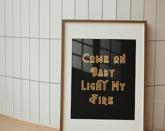 Pode incluir: Uma impressão emoldurada com fundo preto e texto dourado que diz "Come on Baby Light My Fire".
