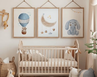 May include: Three framed watercolor prints with a nursery theme. One features a blue hot air balloon with a bear, another a crescent moon with hanging stars and hearts, and the last a blue bunny. A wooden crib and toys complete the scene.