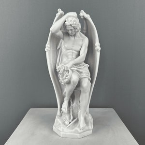 May include: White marble sculpture of a winged angel sitting with a chain around its ankle. The angel is holding a wreath in its hands and has its head resting on its hand.