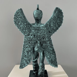 May include: A green winged statue of a mythical creature with a snake wrapped around its leg. The statue is standing on a square base.