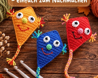 May include: Three crocheted kite-shaped figures in orange, blue, and red, each with white eyes, black pupils, a small round nose, and a stitched smile. Each figure has colorful yarn tassels and a braided tail. Three gray crochet hooks are included.