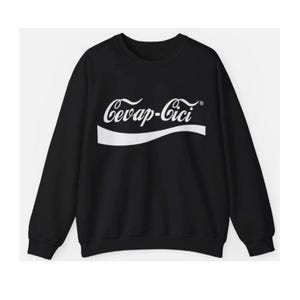 Peut inclure: Un sweat-shirt noir à manches longues avec une impression graphique blanche sur la poitrine. Le motif affiche le texte Cevap-Cici dans une police cursive stylisée, placé au-dessus d'une ligne courbe blanche, rappelant un logo de boisson.