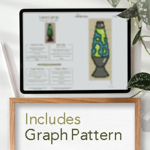 May include: A digital tablet displays a lava lamp cross-stitch pattern. The pattern features a green and blue lava lamp design. A wooden frame below the tablet reads "Includes Graph Pattern" in green text, suggesting a craft project.