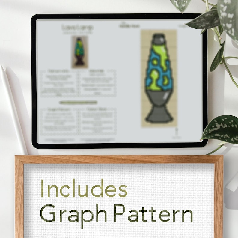 May include: A digital tablet displays a lava lamp cross-stitch pattern. The pattern features a green and blue lava lamp design. A wooden frame below the tablet reads "Includes Graph Pattern" in green text, suggesting a craft project.