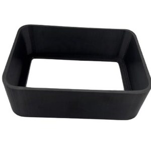 Puede incluir: Un objeto negro de forma cuadrada con un centro hueco. El objeto tiene un acabado liso y mate y parece estar hecho de un material s&oacute;lido. Los lados est&aacute;n ligeramente angulados, lo que le da una forma trapezoidal. El objeto est&aacute; aislado sobre un fondo blanco.