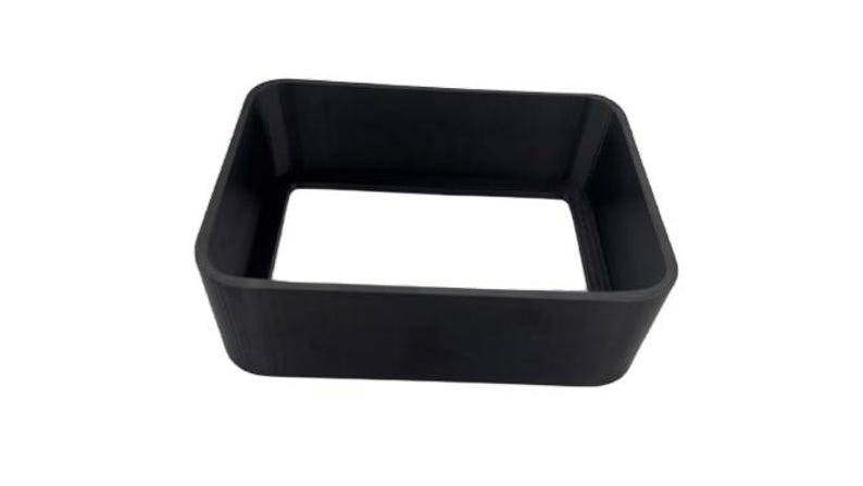 Puede incluir: Un objeto negro de forma cuadrada con un centro hueco. El objeto tiene un acabado liso y mate y parece estar hecho de un material s&oacute;lido. Los lados est&aacute;n ligeramente angulados, lo que le da una forma trapezoidal. El objeto est&aacute; aislado sobre un fondo blanco.