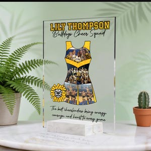 May include: A clear acrylic plaque featuring the name LILY THOMPSON and the text Bulldogs Cheer Squad above a cheer uniform graphic filled with photos of a cheer team. Below is a yellow bulldog mascot and the text The best cheerleaders bring energy, courage, and heart to every game.