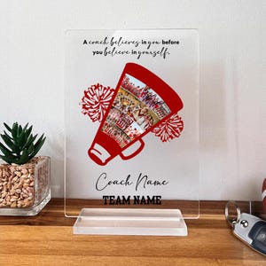 May include: Clear acrylic plaque with a red megaphone design filled with team photos and red pom-poms. The text reads "A coach believes in you before you believe in yourself." Below the megaphone are the words "Coach Name" and "TEAM NAME."