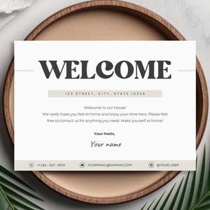 Pu&ograve; includere: Un cartello di benvenuto con il testo "WELCOME" in grassetto nero. Il cartello include anche l'indirizzo "123 STREET, CITY, STATE 12345" e un messaggio di benvenuto. Il cartello &egrave; su un vassoio di legno con uno sfondo bianco.