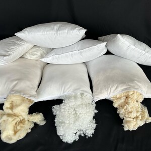 May include: Eight white pillowcases with zippers, some are open to reveal the white and cream-colored filling inside.