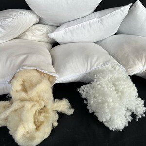 May include: Four white pillowcases with zippers are open to reveal the white and cream-colored filling inside.
