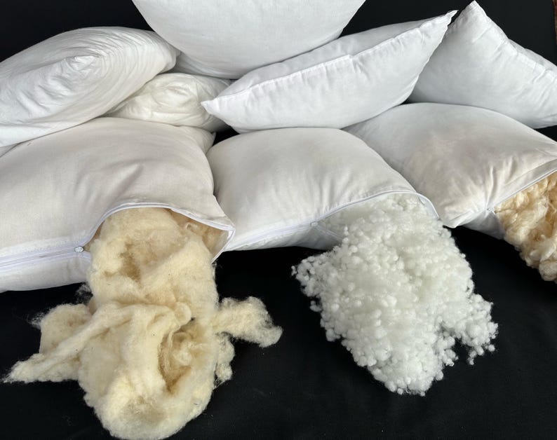May include: Four white pillowcases with zippers are open to reveal the white and cream-colored filling inside.