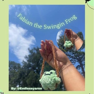 Puede incluir: Dos peluches de crochet colgando de cordones marrones. El primero es una rana verde con el texto "Fabian the Swingin Frog" y "By: @Endlesyarnn". El segundo es un personaje rosa de Kirby con el texto "Swingin Kirby" y "By: @Endlesyarnn".