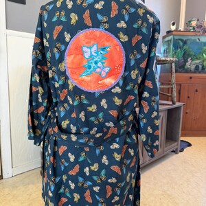 May include: A dark blue robe with a butterfly print and a large orange circle with a lightning bolt and butterflies in the center.