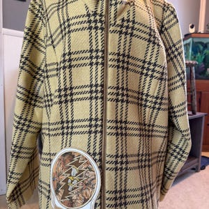 May include: A yellow and black plaid jacket with a zipper closure. The jacket has a patch on the front with a skull and lightning bolt design.