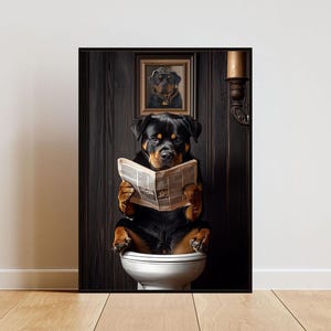 Könnte beinhalten: Gerahmter Druck mit einem Rottweiler, der auf einer Toilette sitzt und Zeitung liest. Der Hund ist schwarz und braun und hat einen ernsten Gesichtsausdruck. Ein kleineres gerahmtes Porträt eines Rottweilers hängt darüber. Der Hintergrund ist dunkles Holz.