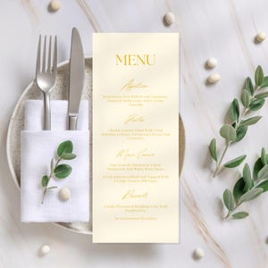 Może przedstawiać: Formalne menu ze złotymi literami, zawierające przystawki, przystawki, dania główne i desery. Menu umieszczone jest obok widelca, noża i złożonej białej serwetki na talerzu. Ozdobne gałązki i makaroniki otaczają menu.