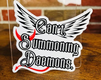 May include: White sticker with black and red graphic design. The design features a pair of wings, a devil's tail, and the text "Can't Summoning Demons".