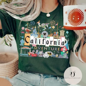 Op de afbeelding: Een groen T-shirt met een kleurrijke afbeelding van een Californi&euml; amusementspark. De afbeelding bevat de tekst "California Adventure" en toont populaire Disney-personages zoals Mickey Mouse, Minnie Mouse en Buzz Lightyear.