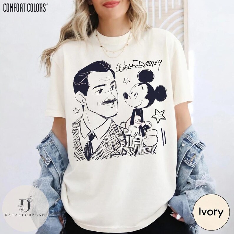 May include: Ivory-colored t-shirt featuring a black and white illustration of Walt Disney and Mickey Mouse. The text "Walt Disney" is written above Mickey Mouse. The shirt has the "Comfort Colors" logo at the top.