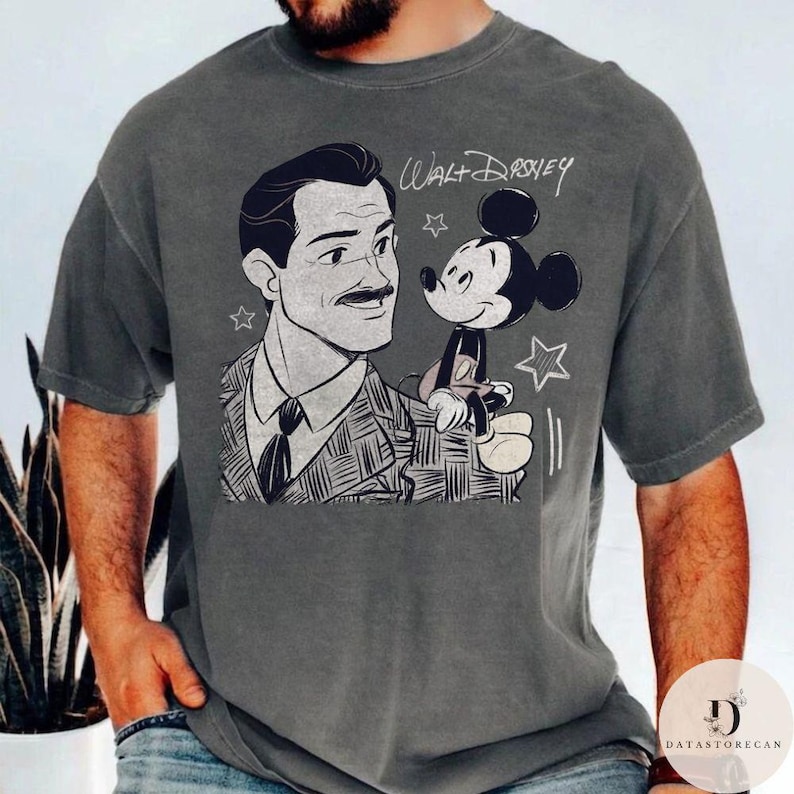 May include: Gray t-shirt featuring a black and white illustration of Walt Disney with Mickey Mouse. The text "Walt Disney" is written above the characters. The shirt has a vintage, distressed look.