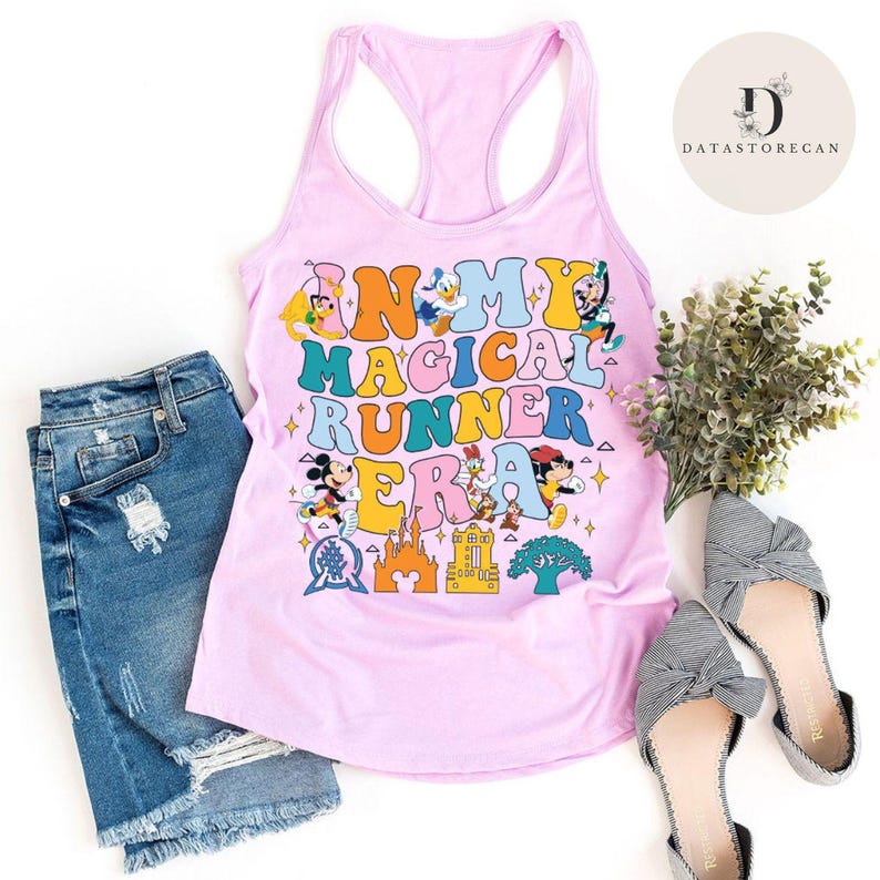 K&ouml;nnte beinhalten: Pinkes Tanktop mit einer bunten Grafik, auf der "In My Magical Runner Era" mit verschiedenen Disney-Charakteren steht. Das Tanktop wird mit Jeans-Shorts und gestreiften Schleifenschuhen kombiniert.