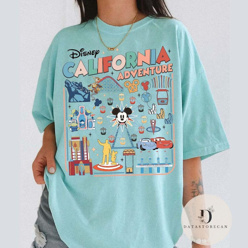 May include: A light blue t-shirt with a colorful graphic design featuring the words "Disney California Adventure" and various theme park icons, including Mickey Mouse, a Ferris wheel, and roller coasters.