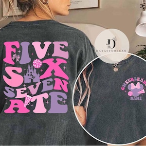 May include: Two gray t-shirts with different designs. The first shirt has a pink, purple, and white design with the words "Five Six Seven Ate". The second shirt has a pink and white design with the words "Cheerleader" and a cartoon mouse with a bow.