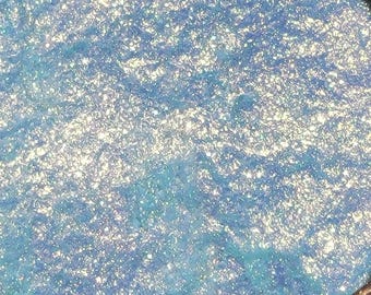 May include: A close-up of a light blue iridescent glitter, with a shimmery, sparkly texture.