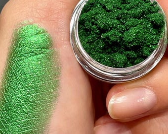 May include: A small jar of green glitter eyeshadow with a sample of the eyeshadow swatched on a hand.