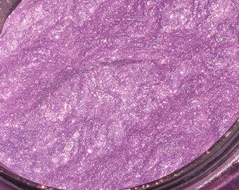 May include: Close-up of a jar of purple glitter with a shimmery finish.