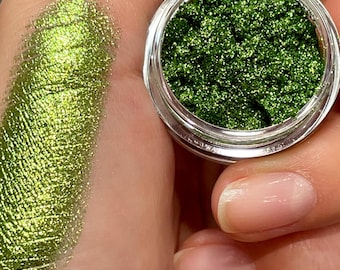 May include: A small jar of green glitter eyeshadow with a sample of the eyeshadow swatched on a hand.