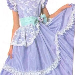 May include: A young girl wearing a lavender dress with a white lace trim and a light blue sash. The dress has a ruffled skirt and short sleeves.