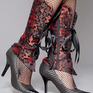 May include: Black high-heeled shoes with a textured pattern and a pointed toe. The shoes are paired with red and black dragon-patterned leg warmers, laced with black ribbons. Fishnet stockings are visible.