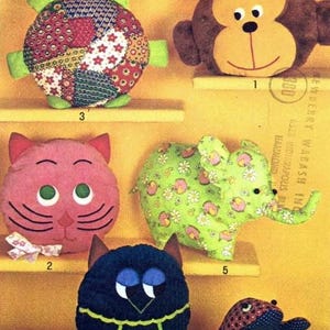 May include: A collection of handmade stuffed animal toys, including a turtle, monkey, cat, elephant, owl, and frog. The toys are made of fabric in various colors and patterns, such as floral and patchwork designs. The toys are displayed on a yellow background.