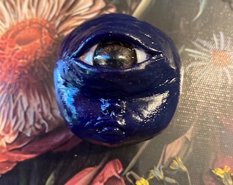 Broche de cíclope con cara de ojo surrealista