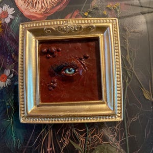 Dark red eye sculpture wall art in gold frame