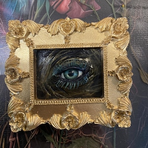 Black and gold eye sculpture wall art in gold frame