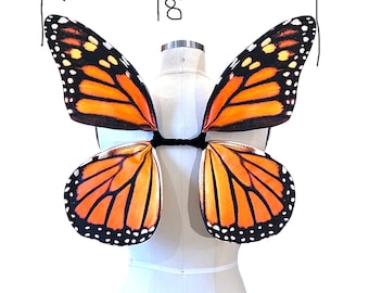 Könnte beinhalten: Orangefarbene und schwarze Schmetterlingsflügel mit einem schwarzen Gummiband zum Anbringen an einem Kostüm. Die Flügel sind 45,72 cm breit.