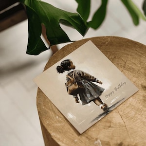 May include: A square greeting card with a watercolor illustration of a young girl walking away, wearing a dress and carrying a backpack. The card has the text "Happy Birthday" in cursive.
